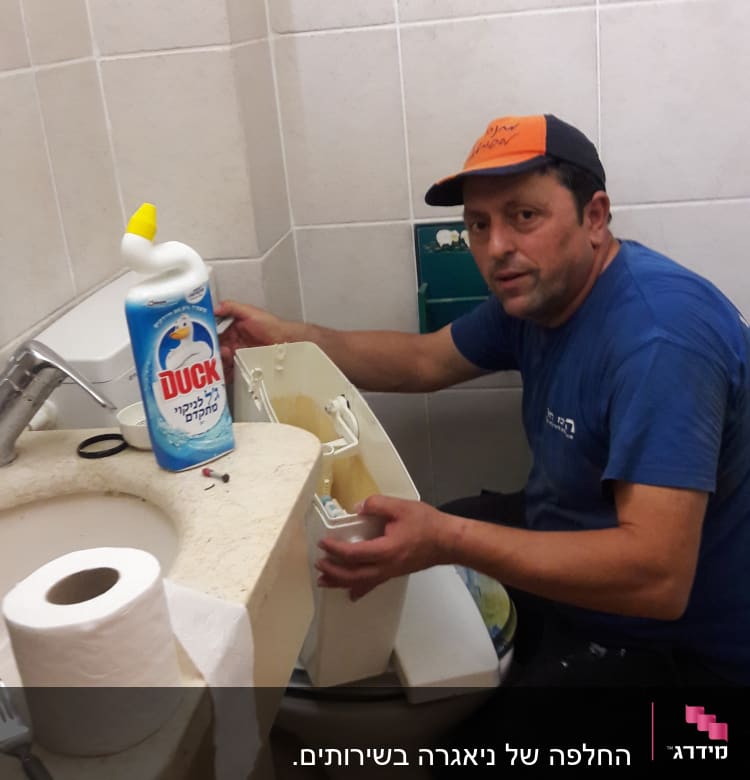 אדם מתקן אסלה בחדר אמבטיה